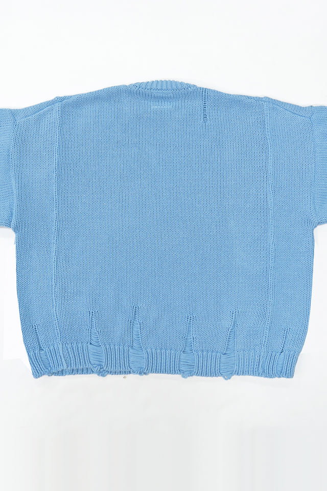 Back view of oversized blue knit sweater showing three panel construction and relaxed silhouette