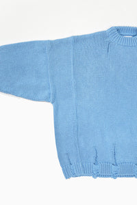 Detail of wide armhole on oversized blue knit sweater showing relaxed fit and panel construction