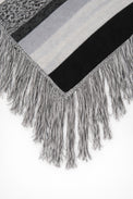Close-up of long fringe detail on black and grey striped knit poncho
