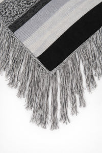 Close-up of long fringe detail on black and grey striped knit poncho