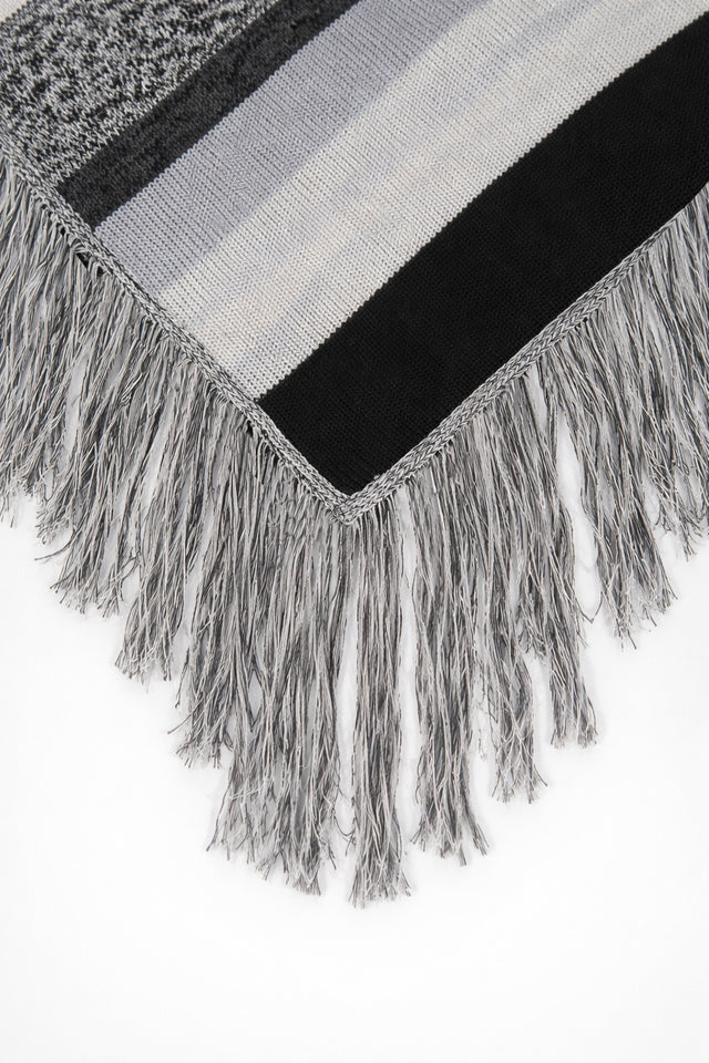 Close-up of long fringe detail on black and grey striped knit poncho