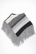 Black and grey striped knit cotton poncho with fringe laid flat on light grey background