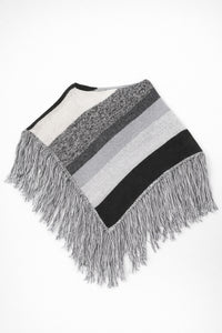 Black and grey striped knit cotton poncho with fringe laid flat on light grey background