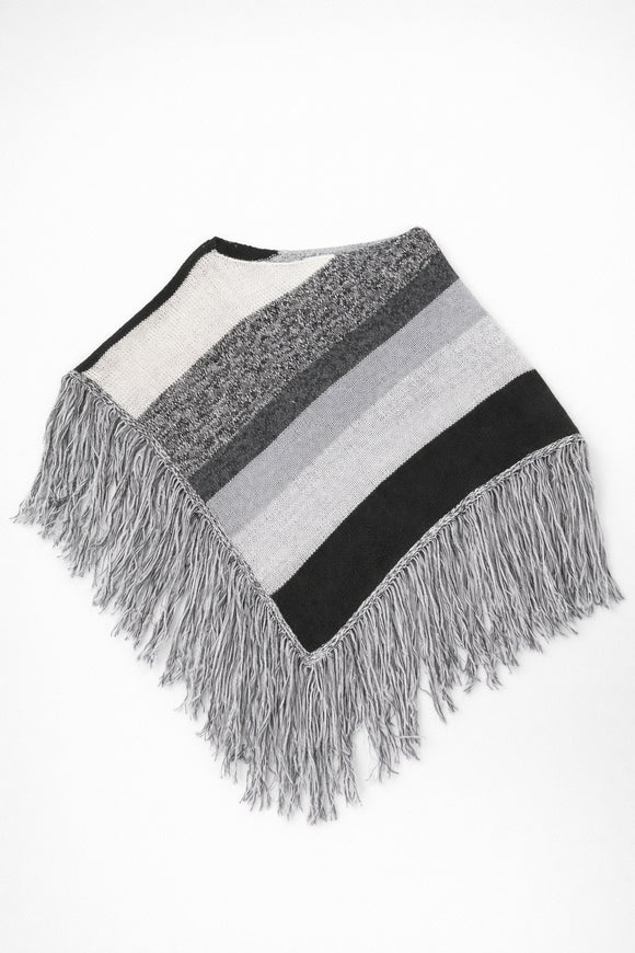 Black and grey striped knit cotton poncho with fringe laid flat on light grey background