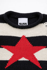 Detail of rollneck, round, neckline of black and cream striped distressed sweater with intarsia red star by Suss Knits