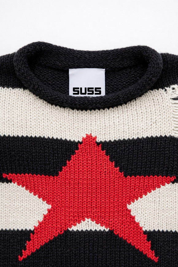 Detail of rollneck, round, neckline of black and cream striped distressed sweater with intarsia red star by Suss Knits