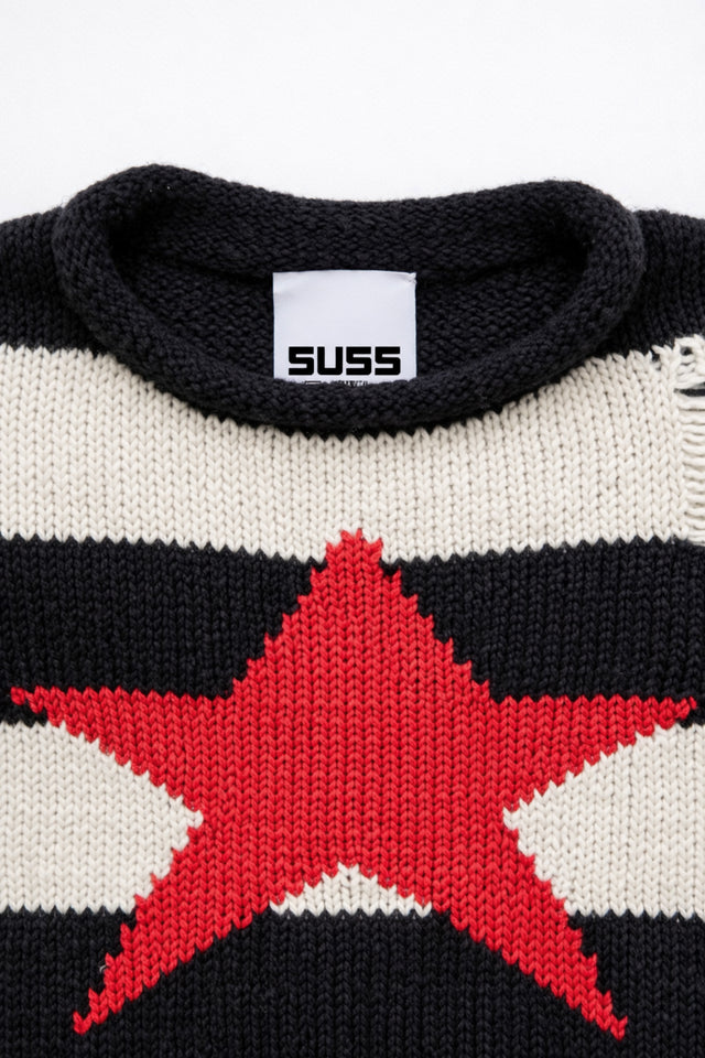 Detail of rollneck, round, neckline of black and cream striped distressed sweater with intarsia red star by Suss Knits