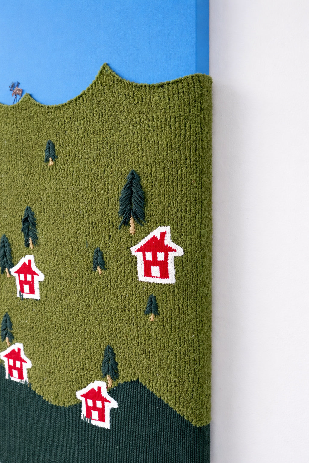 Close-up of hand loomed boucle wool textile with embroidered tree details