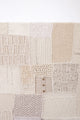 Close-up of hand knit patchwork textile wall art showing mixed stitch patterns and textures in neutral cream tones