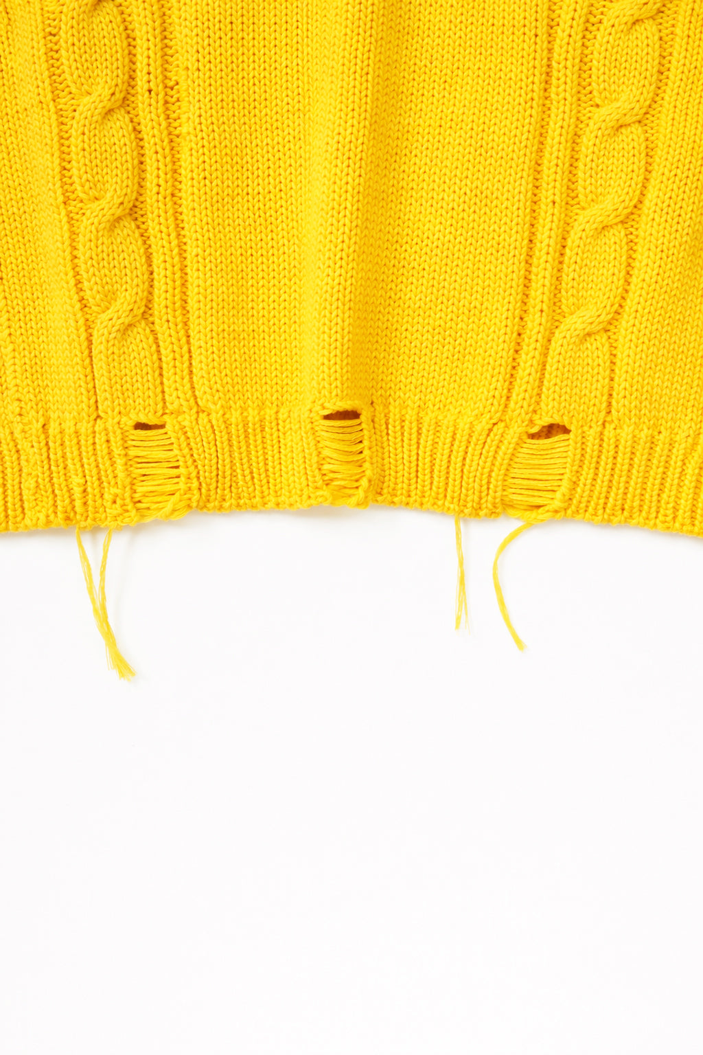 Hem detail photo of distressing on the yellow cable knit sweater hand loomed in Los Angeles