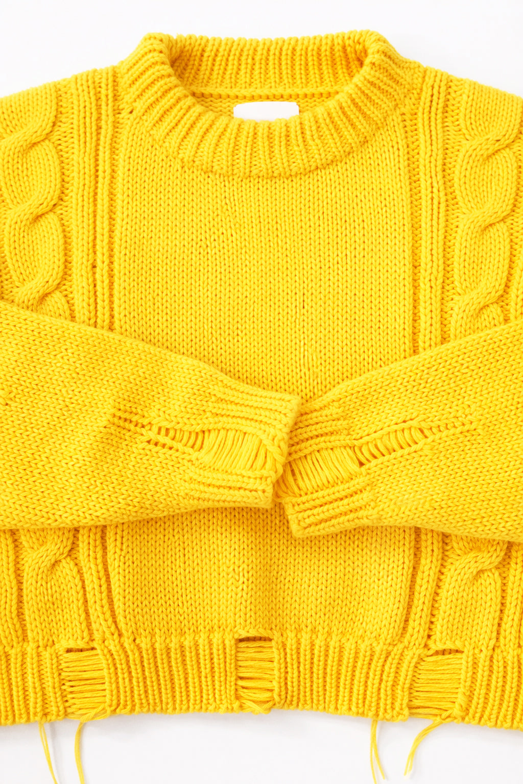 Close up of the Suss Knits yellow knit cable sweater cuffs and distressing