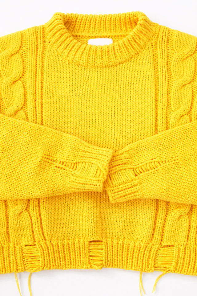 Close up of the Suss Knits yellow knit cable sweater cuffs and distressing
