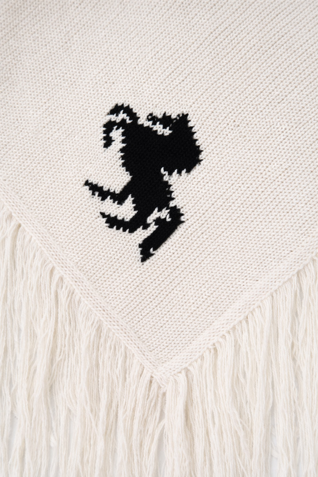horse motif detail on cream knit poncho close up