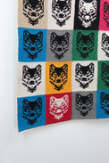 Angled detail of colorful wolf knit panels in grid layout on cotton fiber wall hanging