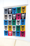 Modern knit wolf wall hanging displayed above a neutral sofa in minimalist interior